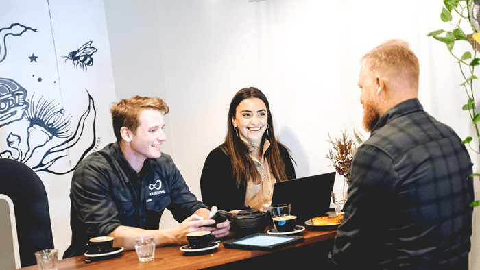 three people sitting around a cafe table talking and laughing 