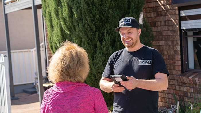 man standing in front yard talking and smiling with customer