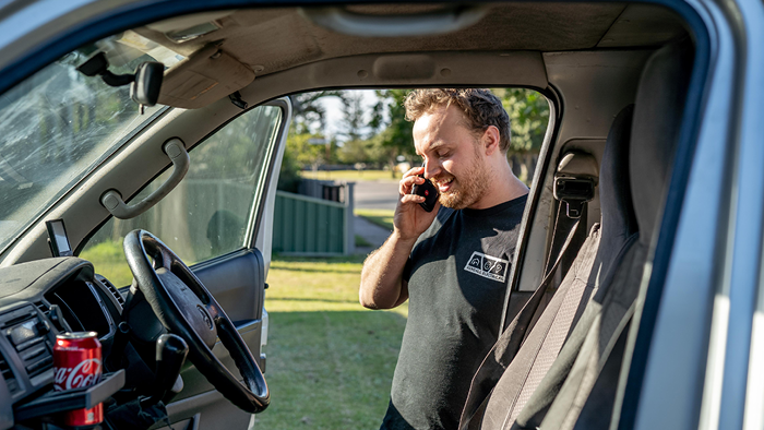 electrician talking on cell phone while getting out of car 