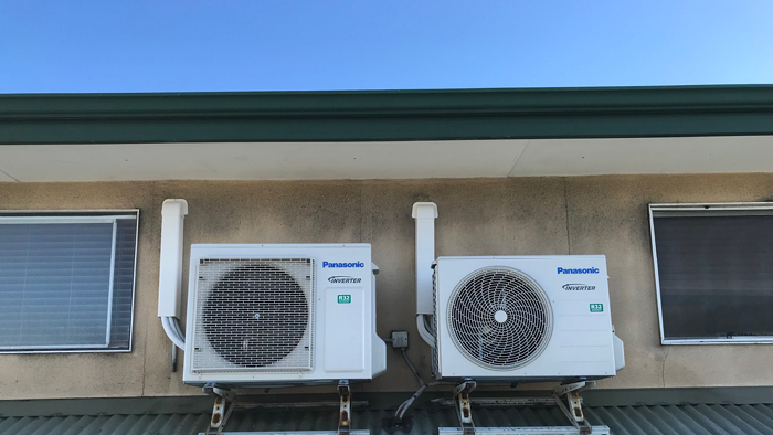 two Panasonic air conditioning units attached to side of house