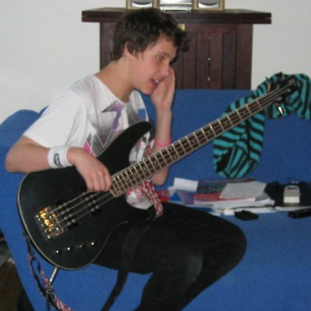 Tom practising playing a black bass guitar