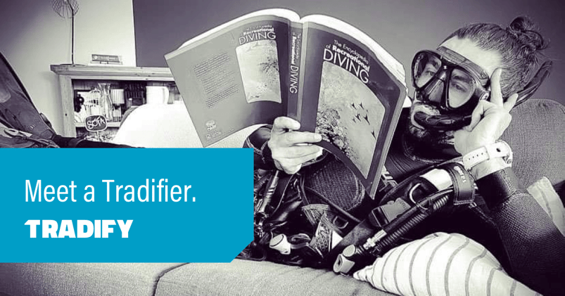 Mik lies on the sofa wear scuba gear and reading The Encyclopedia of recreational diving