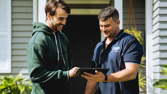 Blog_Social media ideas for builders and construction workers _business owner looking at device with customer and smiling