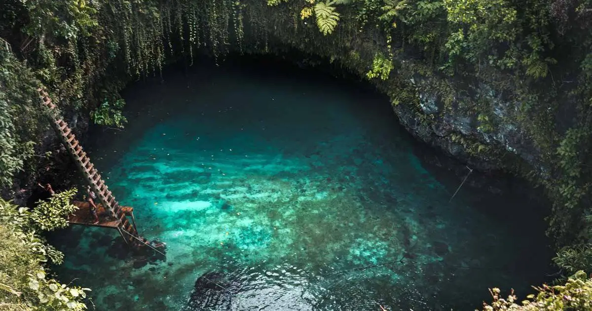 A ladder leads to clear blue waters at a swimming hole in Samoa
